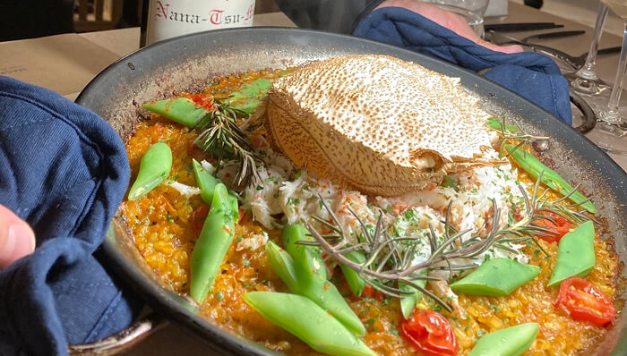 カニの甲羅を中央に据えた豪華なパエリア風料理が大皿に盛られている